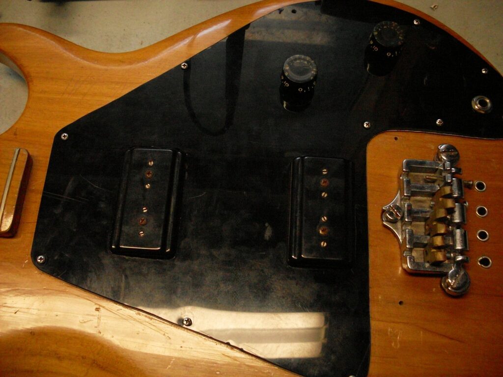 Close-up of a natural-finish Gibson Ripper bass body showing its two pickups, control knobs and bridge